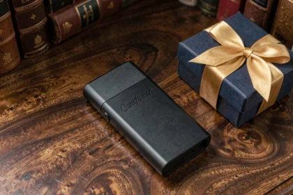 Briquet luxueux noir mat posé sur une surface en bois sombre avec une boîte cadeau élégante ruban doré